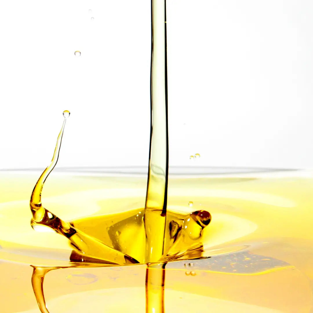 Yellow oil being poured with a white background
