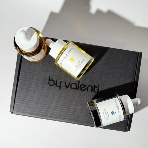 Three By Valenti serum bottles on a 'by valenti' branded box with a neutral background