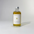 Glass bottle of BY VALENTI Olive Facial Cleansing Oil makeup remover with aluminium cap on white background