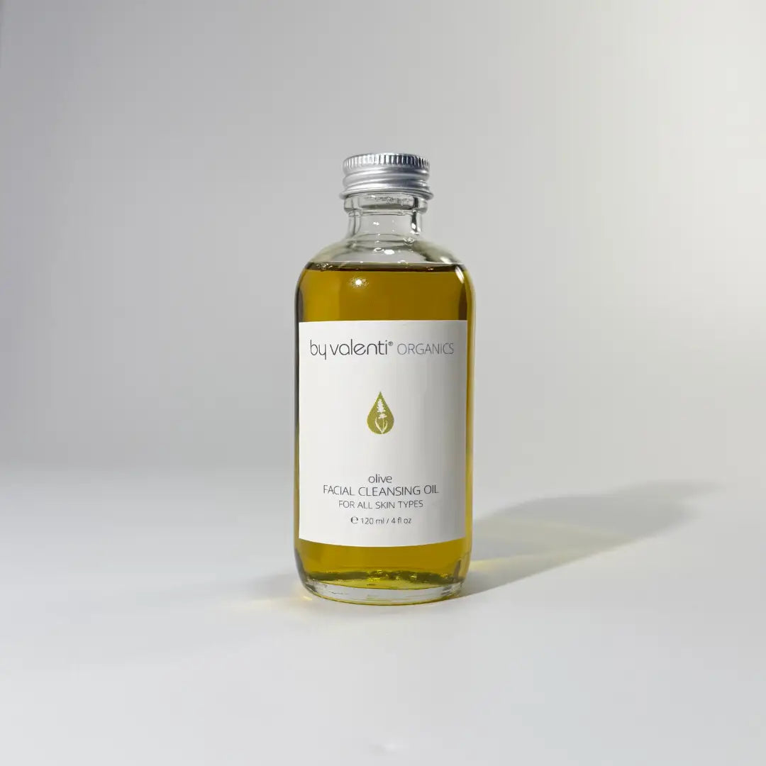 Glass bottle of BY VALENTI Olive Facial Cleansing Oil makeup remover with aluminium cap on white background