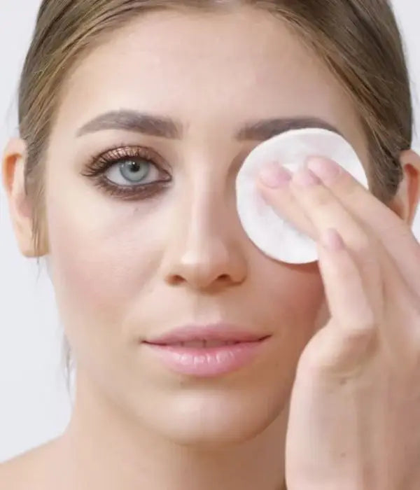 Woman removing makeup off her eye with a cotton pad