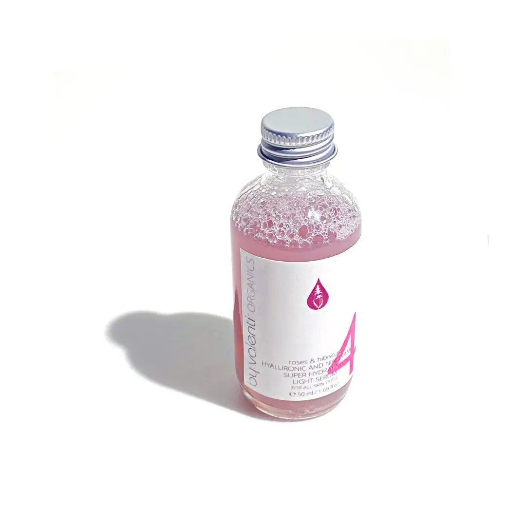 Bottle of By Valenti Italian serum with a pink liquid and a white label on a white background