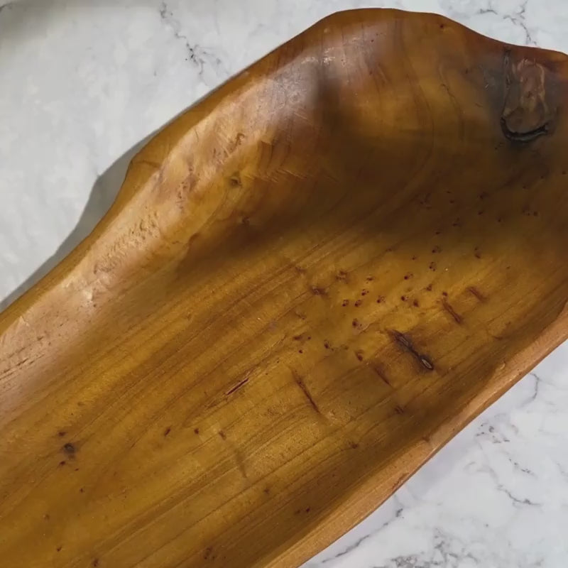 An olive wood tray holding a bottle of By Valenti's Castile Liquid soap and two bars of By Valenti Organics Castile soap on a white marble table